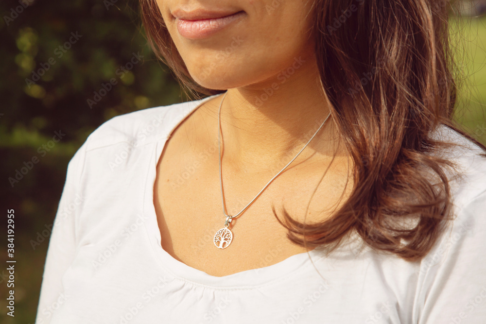 Female neckline wearing tiny silver chain with silver pendant in the shape of tree in mandala Female neckline wearing tiny silver chain with silver pendant in the shape of tree in mandala