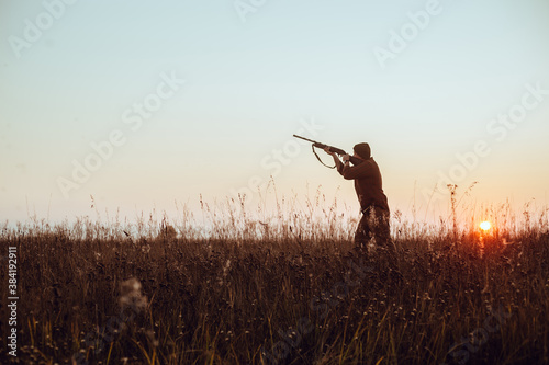 Hunter's dark silhouette with blue sky and red sun - photo with selective focus