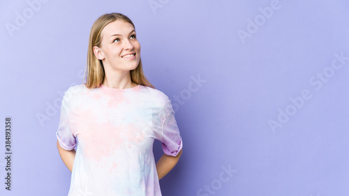 Young blonde woman isolated on purple background relaxed and happy laughing  neck stretched showing teeth.