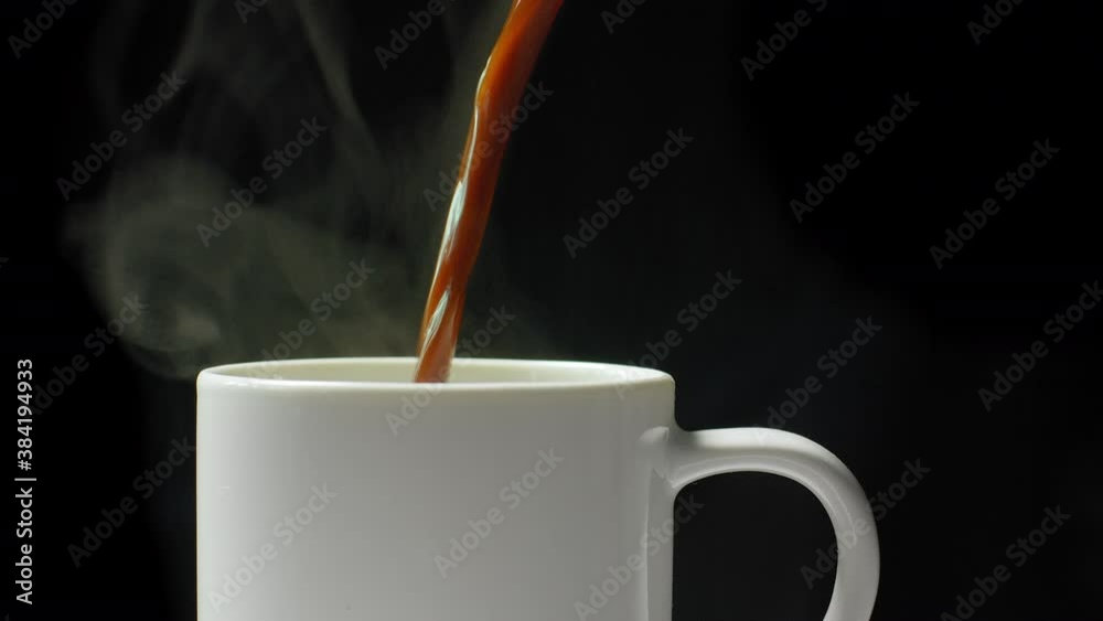 Coffee is poured into a mug. 
Fresh espresso in a cup on black background