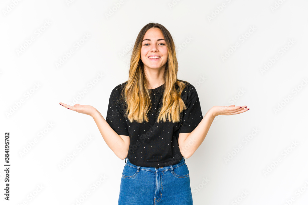 Young caucasian woman isolated on white background makes scale with arms, feels happy and confident. Young caucasian woman isolated on white background makes scale with arms, feels happy and confident.
