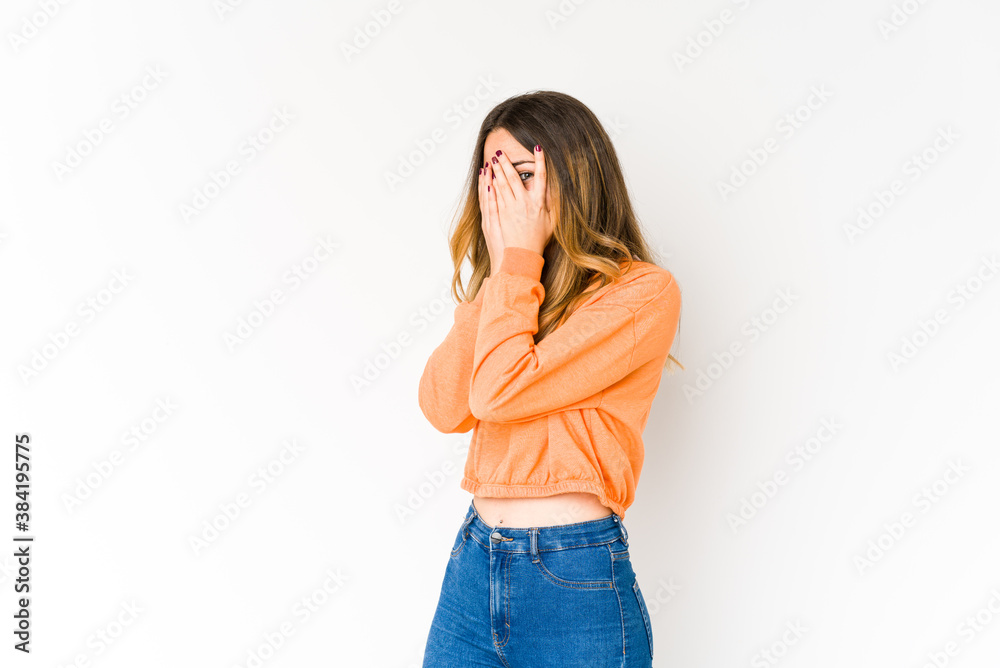 Young caucasian woman isolated on white background blink through fingers frightened and nervous. Young caucasian woman isolated on white background blink through fingers frightened and nervous.