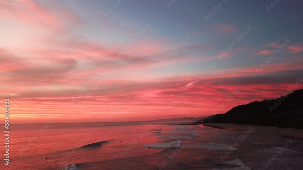 People enjoying the red waves during a fiery sunset in Santa Teresa, Costa Rica People enjoying the red waves during a fiery sunset in Santa Teresa, Costa Rica