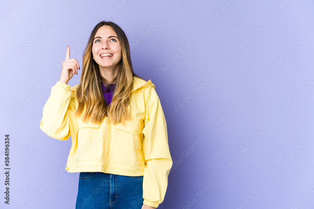 Young caucasian woman isolated on purple background indicates with both fore fingers up showing a blank space. Young caucasian woman isolated on purple background indicates with both fore fingers up showing a blank space.