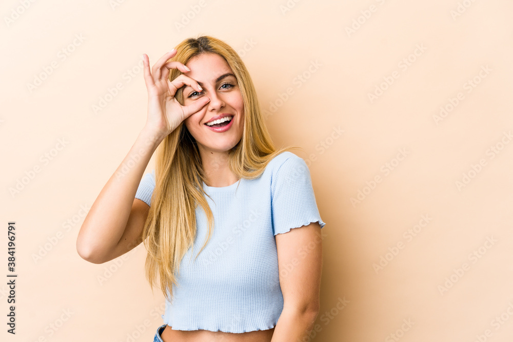 Young blonde caucasian woman excited keeping ok gesture on eye. Young blonde caucasian woman excited keeping ok gesture on eye.