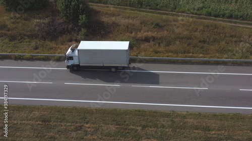 Wallpaper Mural Aerial shot of truck with cargo trailer driving on empty straight road. Flying over white lorry moving along highway passing in countryside. Concept of logistic and delivery. Side view Slow motion Torontodigital.ca
