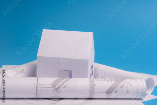 White family paper house over block of flats on blue background paper. Minimalistic and simple concept, style. Copy space. Vertical orientation.