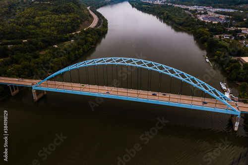 This is an aerial view of the four-lane blue-painted steel arch Moundsville Bridge over the still waters of the Ohio River between Ohio and Moundsville, West Virginia. photo