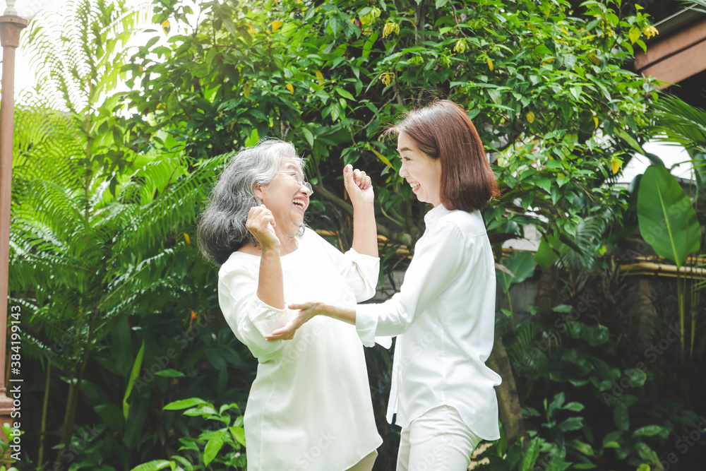 Obraz premium Daughter caring for elderly Asian mother Both of them exercised in the front garden. Make it healthy, strong, a happy family. Senior care concept in retirement age