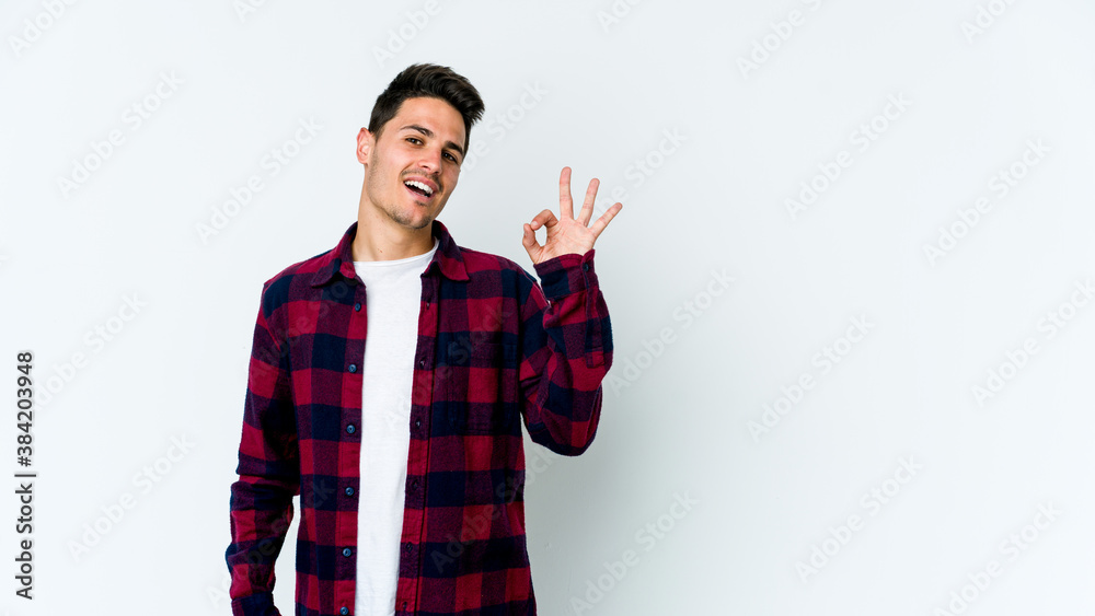 Young caucasian man isolated on white background winks an eye and holds an okay gesture with hand. Young caucasian man isolated on white background winks an eye and holds an okay gesture with hand.