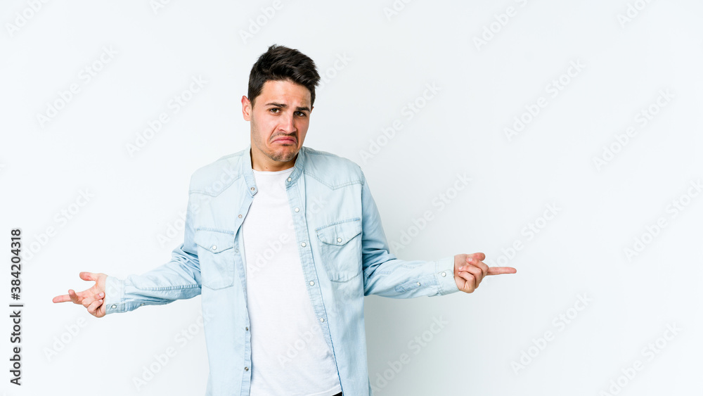 Young caucasian man isolated on white background doubting and shrugging shoulders in questioning gesture. Young caucasian man isolated on white background doubting and shrugging shoulders in questioning gesture.