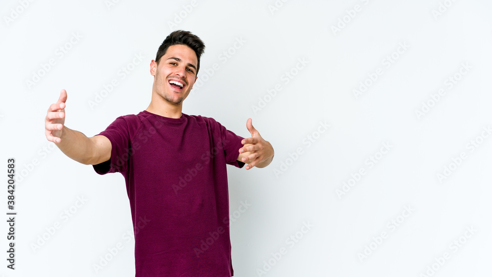 Young caucasian man isolated on white background feels confident giving a hug to the camera.