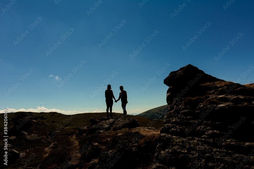 Silhouette of a couple on top of a mountain, tourists on top of a Carpathian mountain, Montenegrin ridge.