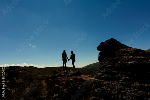 Silhouette of a couple on top of a mountain  tourists on top of a Carpathian mountain  Montenegrin ridge.