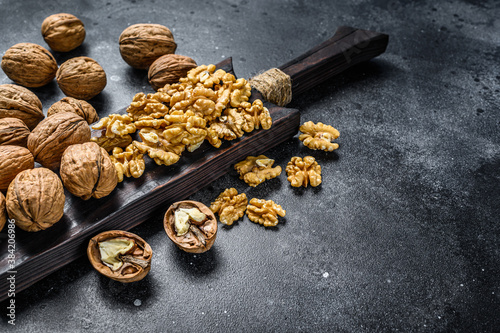 Shelled walnuts kernels on wooden cutting board. Black background. Top view. Copy space