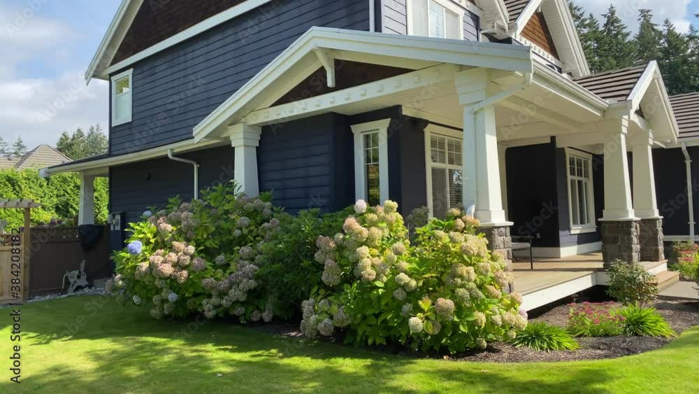 Establishing shot of two story painted wood luxury house with veranda, big tree and nice landscape in Vancouver, Canada, North America. Day time on September 2020. Pan right.