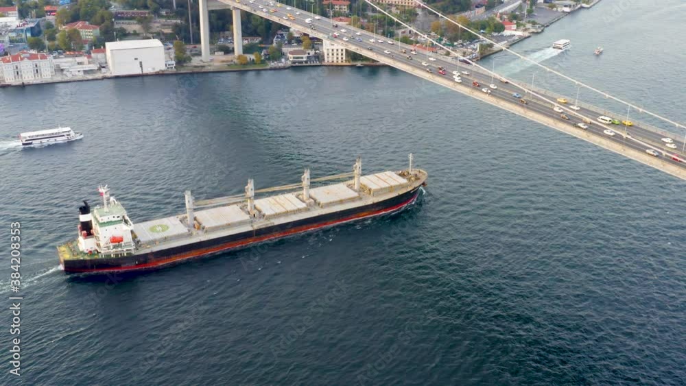 Cargo ship sailing under the Bosporus bridge. A bulk carrier or bulker - a merchant ship specially designed to transport unpackaged bulk cargo, such as grains, ore, coal or timber. Aerial view Cargo ship sailing under the Bosporus bridge. A bulk carrier or bulker - a merchant ship specially designed to transport unpackaged bulk cargo, such as grains, ore, coal or timber. Aerial view