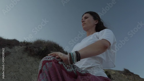 Low angle. Young woman doing yoga, ashwa sanchaalanasana equestrian pose, on sandy beach on early morning. High quality 4k footage photo