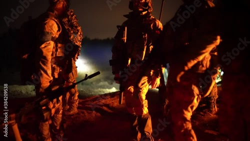 A group of soldiers in a field camp by the fire at night. Military operations at night. Night vision equipment.