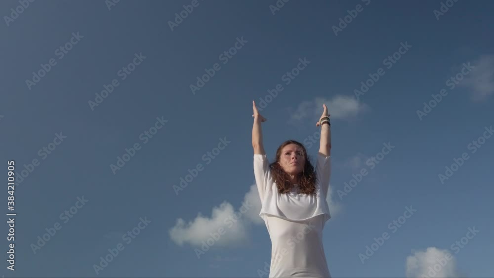Young woman practising yoga on rock against blue sky. High quality 4k footage
