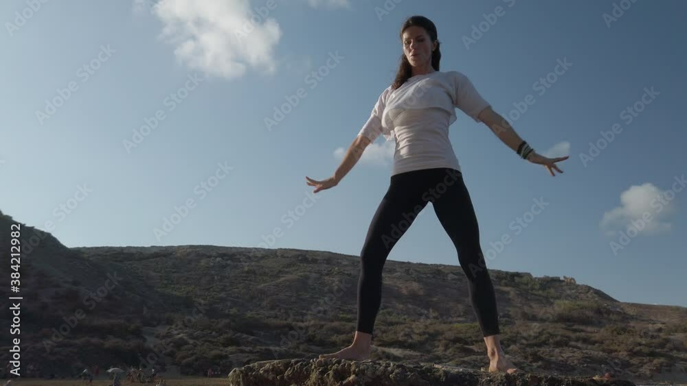 Young caucasian woman practising yoga on the rocky beach. High quality 4k footage Young caucasian woman practising yoga on the rocky beach. High quality 4k footage