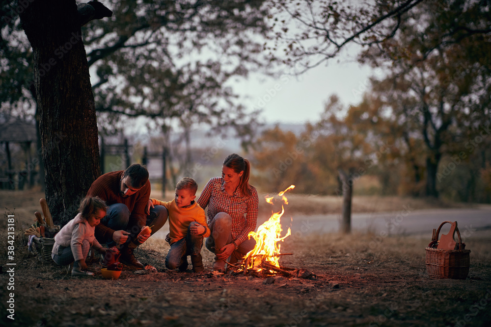 A happy family enjoying together around campfire in the forest A happy family enjoying together around campfire in the forest