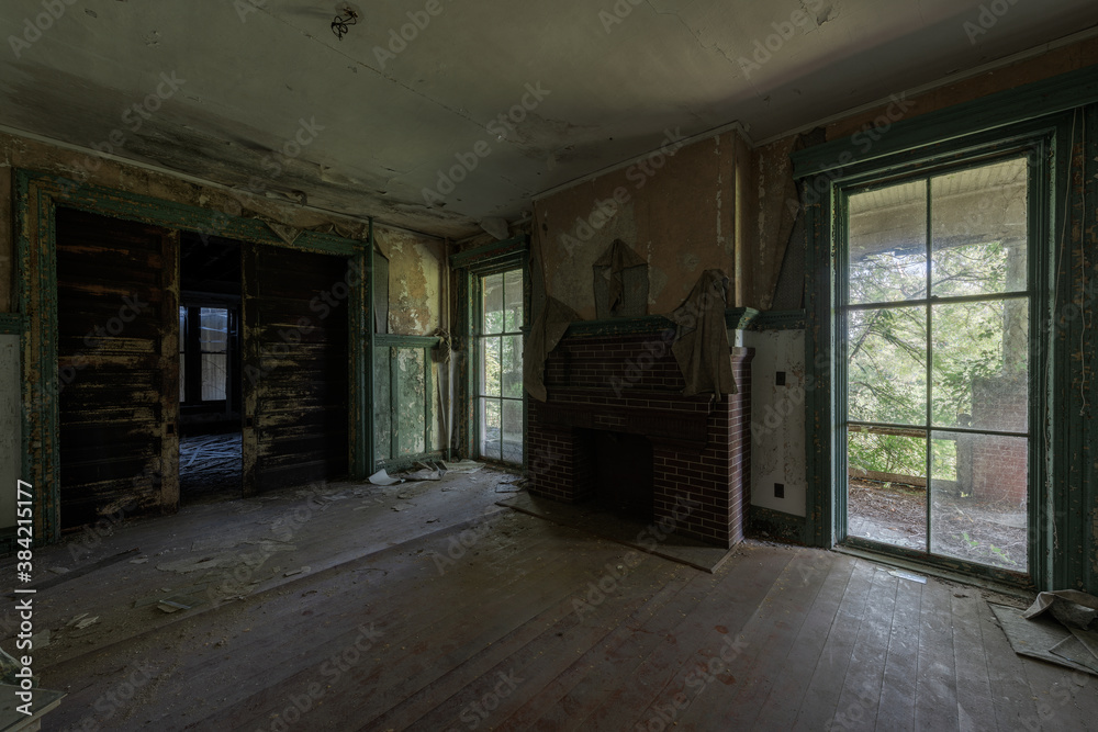 This is an interior view of tall and wide glass windows in the formal dining room at the long-abandoned and historic Dunnington Mansion in Farmville, Virginia.