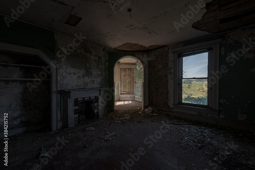 This is an interior view of a corner bedroom with a fireplace at the long-abandoned and historic Dunnington Mansion in Farmville, Virginia.