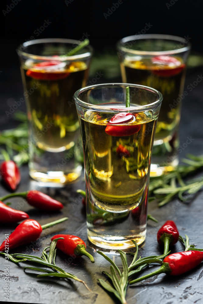 Frozen glass with cold vodka with pepper on dark table Frozen glass with cold vodka with pepper on dark table