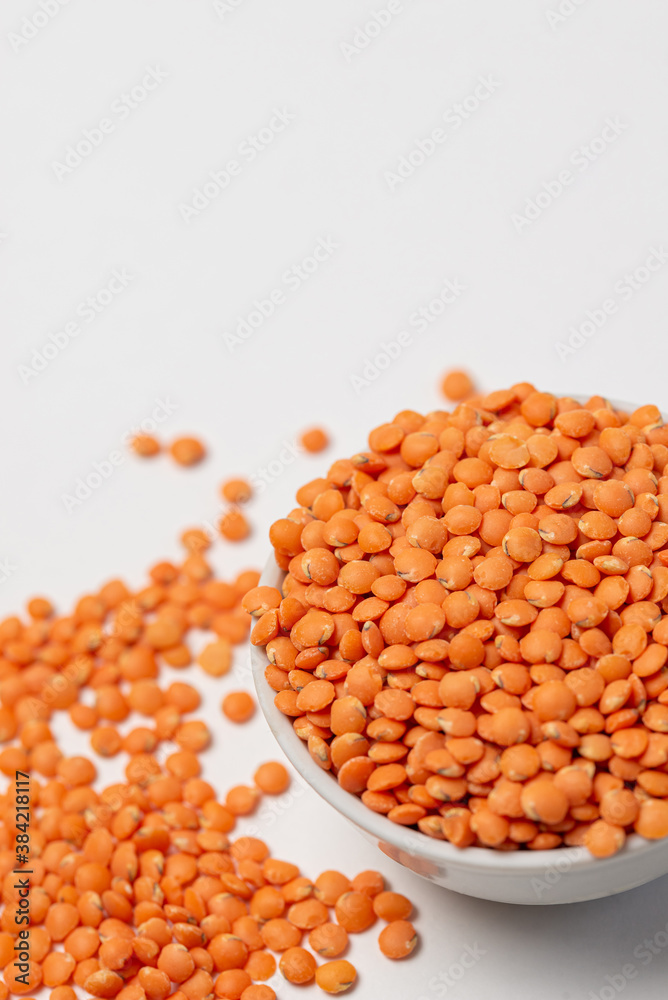 Red lentils in a white bowl on a white background Red lentils in a white bowl on a white background