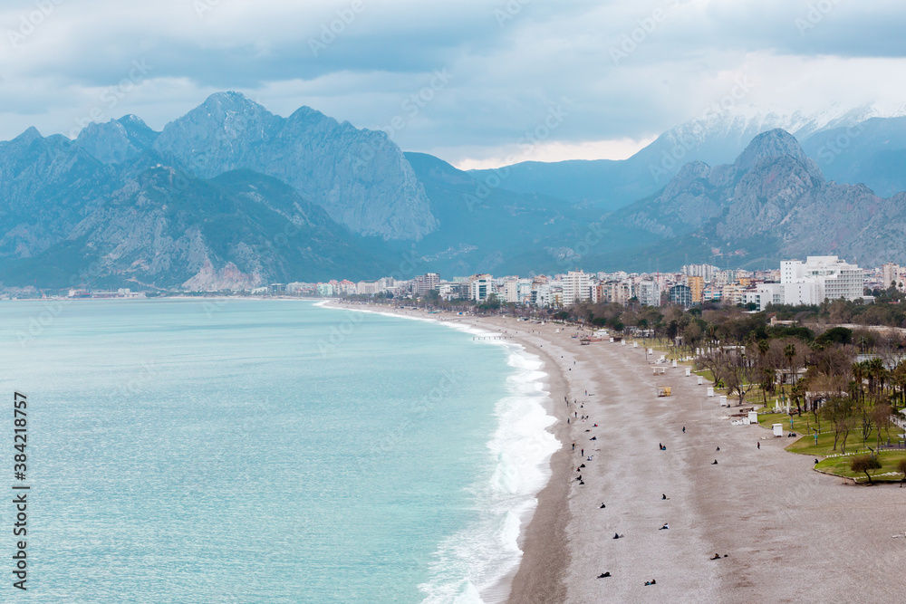 Scenic view of famous turkish Konyaalti Beach in the overcast weather, clouds cover the mountains. Antalya, Turkey