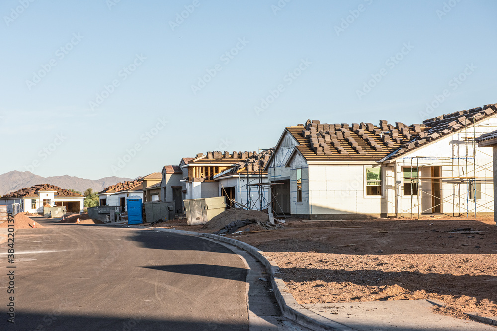 A row of new houses, being constructed during Arizona building boom, stands in early morning light on a dirt lot, horizontal view. A row of new houses, being constructed during Arizona building boom, stands in early morning light on a dirt lot, horizontal view.