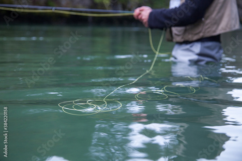 A close up of a fly fisherman holding a rod and reel while wading in the water in Squamish, British Columbia