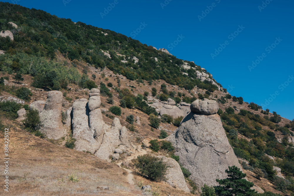 Ridge of brown rocks covered with greenery against a blue sky