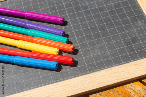 Different colors of felt-tip pencils and chalkboard slate
