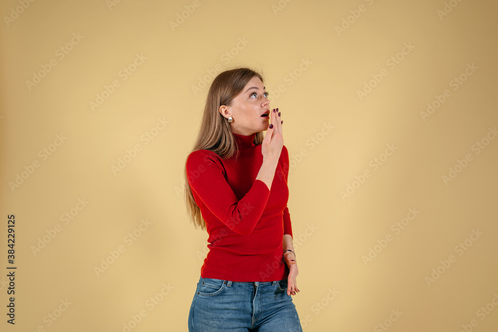 Close up portrait of dumbfounded girl looks to the side touching the palm of her cheek and can not believe the news isolated on yellow background Close up portrait of dumbfounded girl looks to the side touching the palm of her cheek and can not believe the news isolated on yellow background