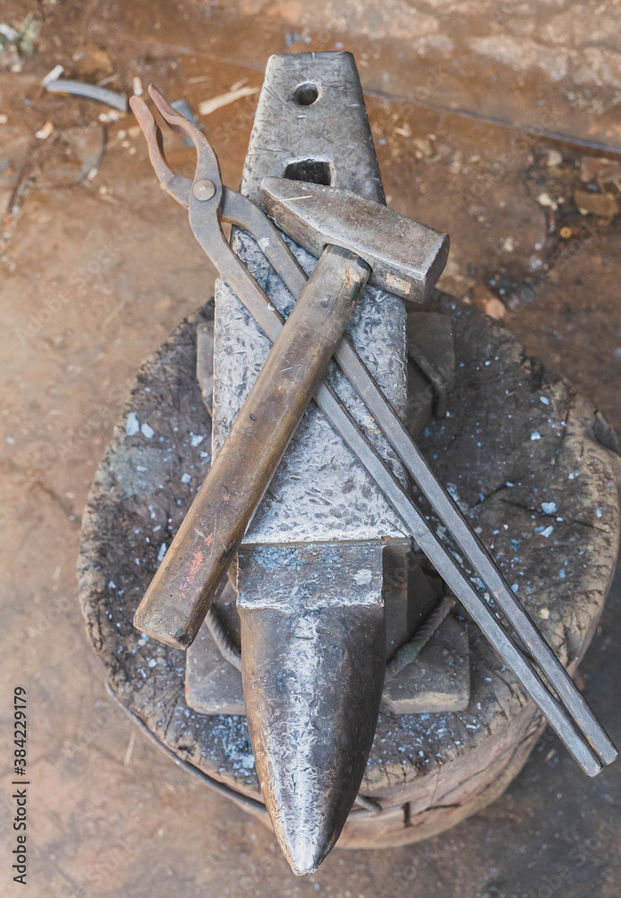 hammer and tongs lie on an anvil in a workshop hammer and tongs lie on an anvil in a workshop