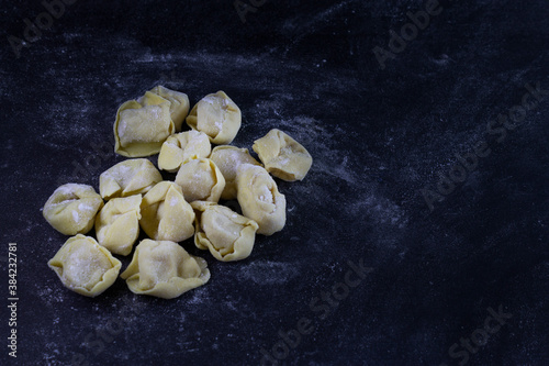 Fresh Ravioli on floury dark background. Italian homemade healthy food concept.Process of making italian ravioli.Place for text , copy space.