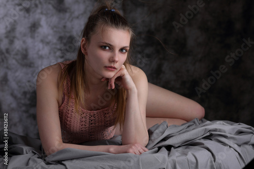 Portrait of a beautiful girl in a pink blouse on gray sheets