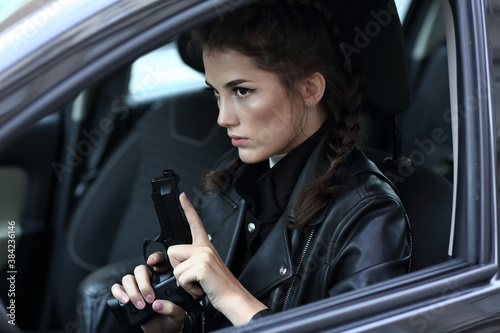 Fotografie, Obraz Girl driving a car with a gun in her hands