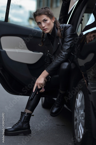 Fotografie A girl in the driver's seat of a car with a gun in her hands