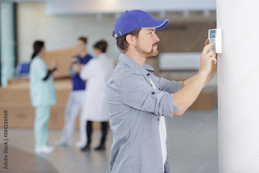 male technician installing alarm system indoors male technician installing alarm system indoors