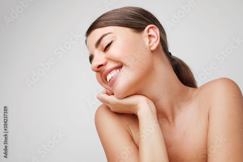 Close-up portrait of young pretty woman, she is smiling and posing in the studio. Space for text.