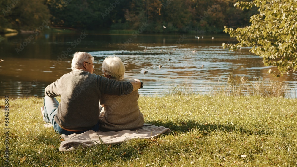 Elderly gray haired couple siting on the bench near the river on autumn day. High quality photo Elderly gray haired couple siting on the bench near the river on autumn day. High quality photo