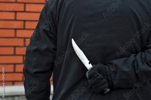 Man with the knife behind his back. Man holding sharp knife behind his back