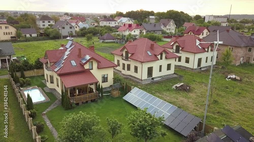 Wallpaper Mural Aerial view of suburban homes and private house with green grass covered yard, solar panels on roof, swimming pool with blue water and wind turbine generator. Torontodigital.ca