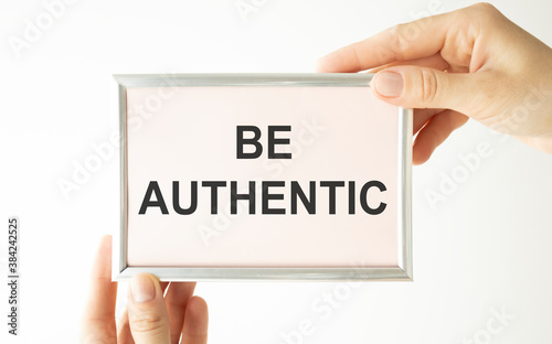 Businesswoman holding a card with text Be Authentic in the hands photo
