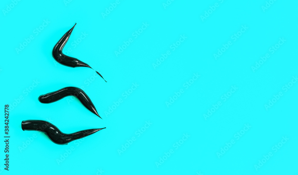 Three thick black cream smears (charcoal toothpaste) on light blue background, view from above, space for text right side Three thick black cream smears (charcoal toothpaste) on light blue background, view from above, space for text right side