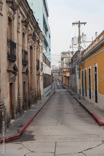 Narrow empty street of colonial city early in the morning on a cloudy day - street of historic center of Quetzaltenango Guatemala