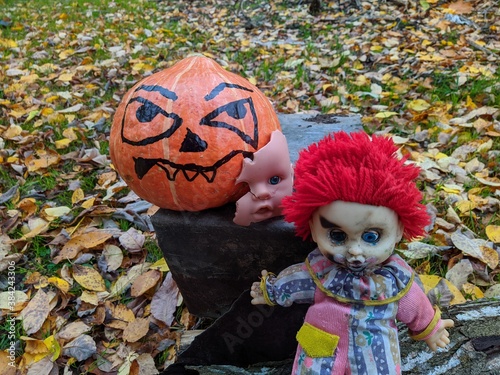 halloween pumpkin with a gang of scary toys on a background of autumn foliage photo